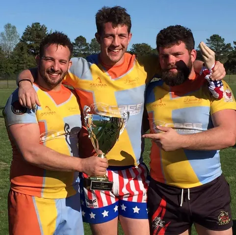Three friends posing with a trophy